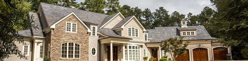 Large stone house with wooden garages and driveway